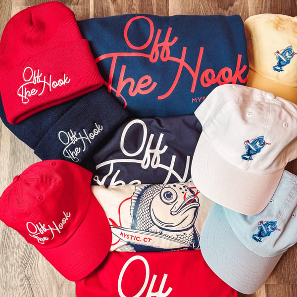 A collection of Off The Hook branded apparel, including beanies, baseball caps, and t-shirts.